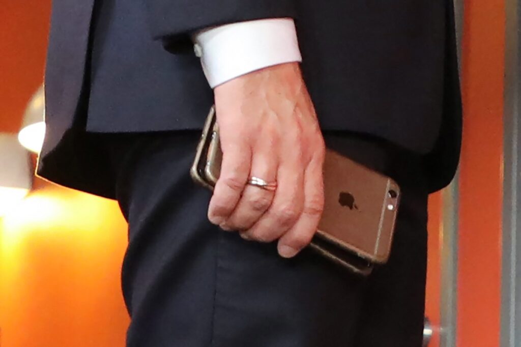 France's President Emmanuel Macron holds his mobile phones while talking with Slovakia's Prime minister during the European Social Summit in Gothenburg, Sweden
